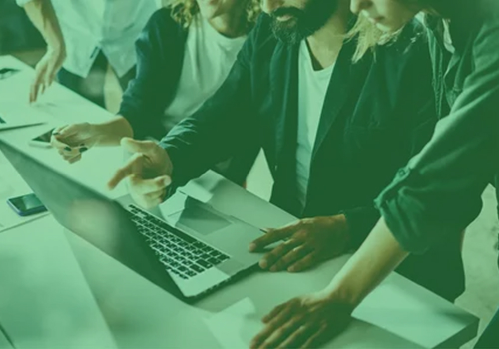 A team of developers collaborating on a project using a laptop, highlighting teamwork at a web app development company in New York.